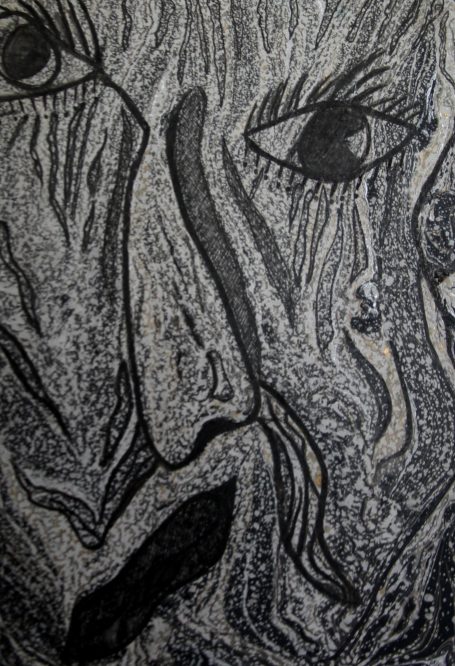 Visage d'un homme avec des traits marqués et une expression intense, en noir et blanc.